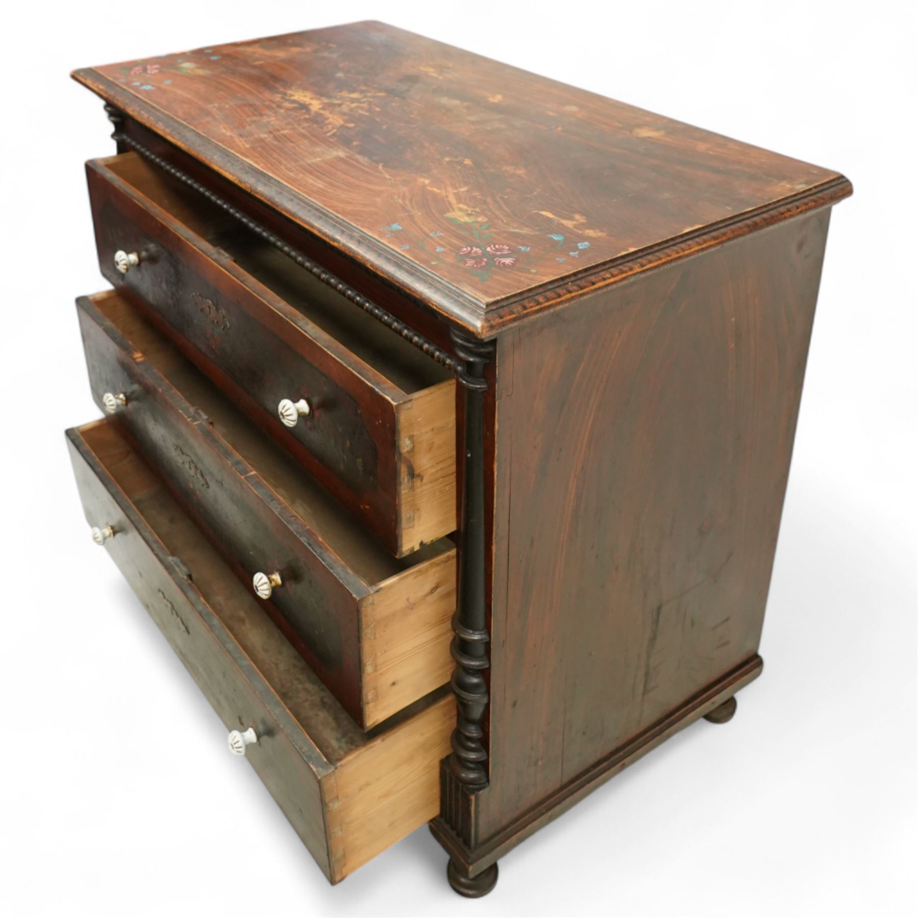 19th century painted pine chest of drawers, the rectangular top with moulded edge and painted floral decoration, above three drawers with later ceramic handles, with half turned column and reeded pilasters, upon turned compressed bun feet  
