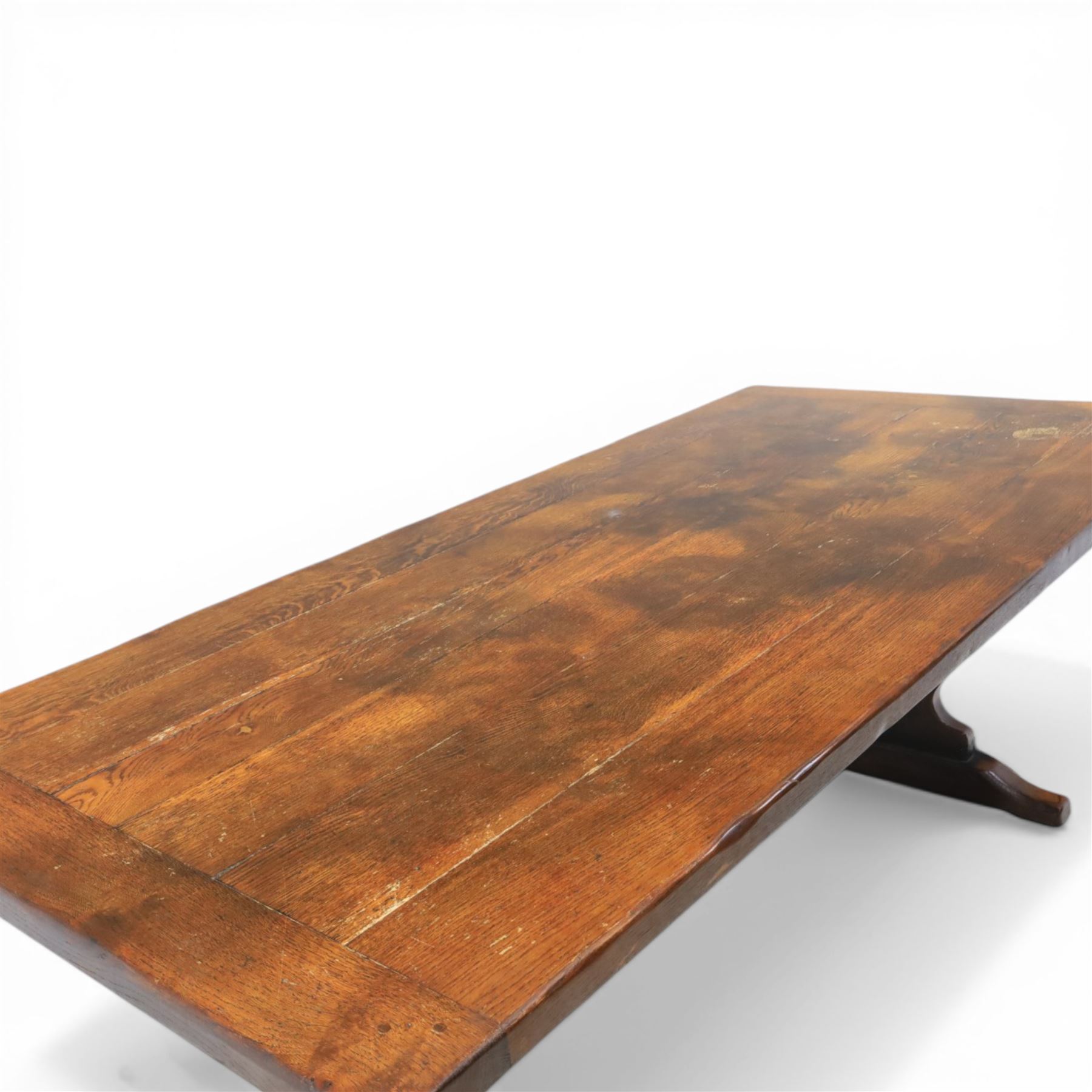 Carolean revival oak dining table and eight chairs (7+1), refectory table with rectangular boarded top and cleated ends, raised on shaped trestle end supports with central stretcher, accompanied by eight high-back chairs including a carver, leather upholstered panels and seats with studwork, on turned legs with stretchers.