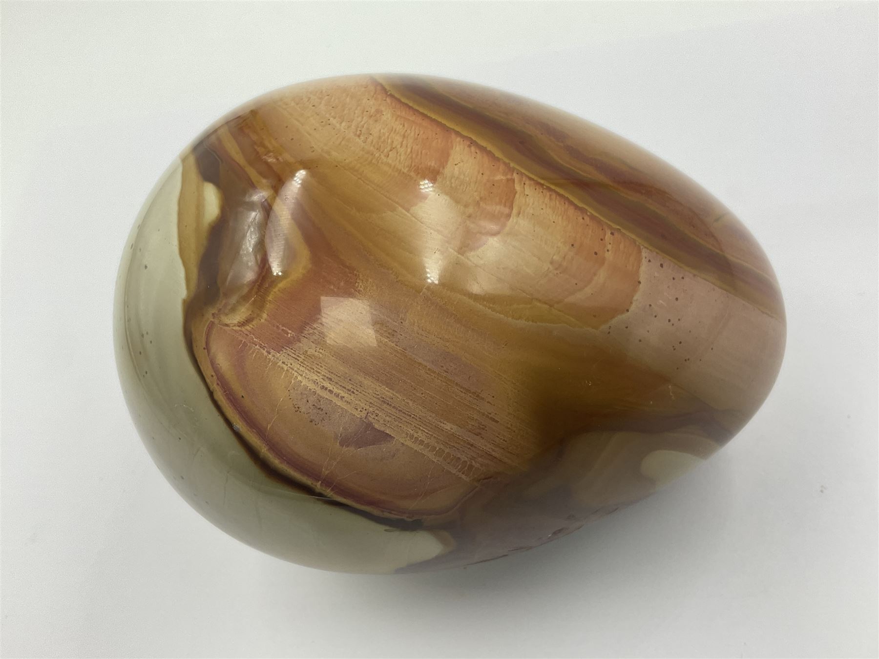 Polychrome jasper specimen egg, in creams, browns and earthy tones, upon a wooden stand, H12cm