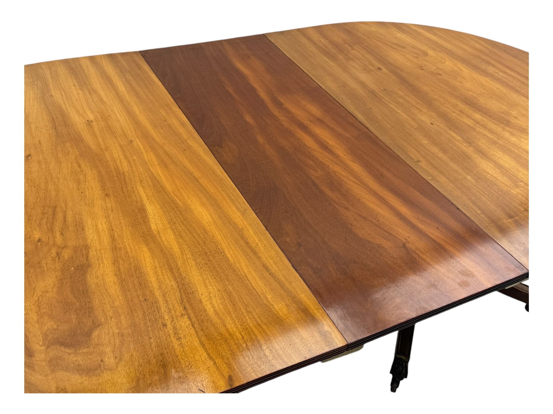 Georgian design mahogany twin pedestal dining table, oval top with reeded edge, single additional leaf, on turned pedestal with four out splayed supports, cast brass hairy paw castors 