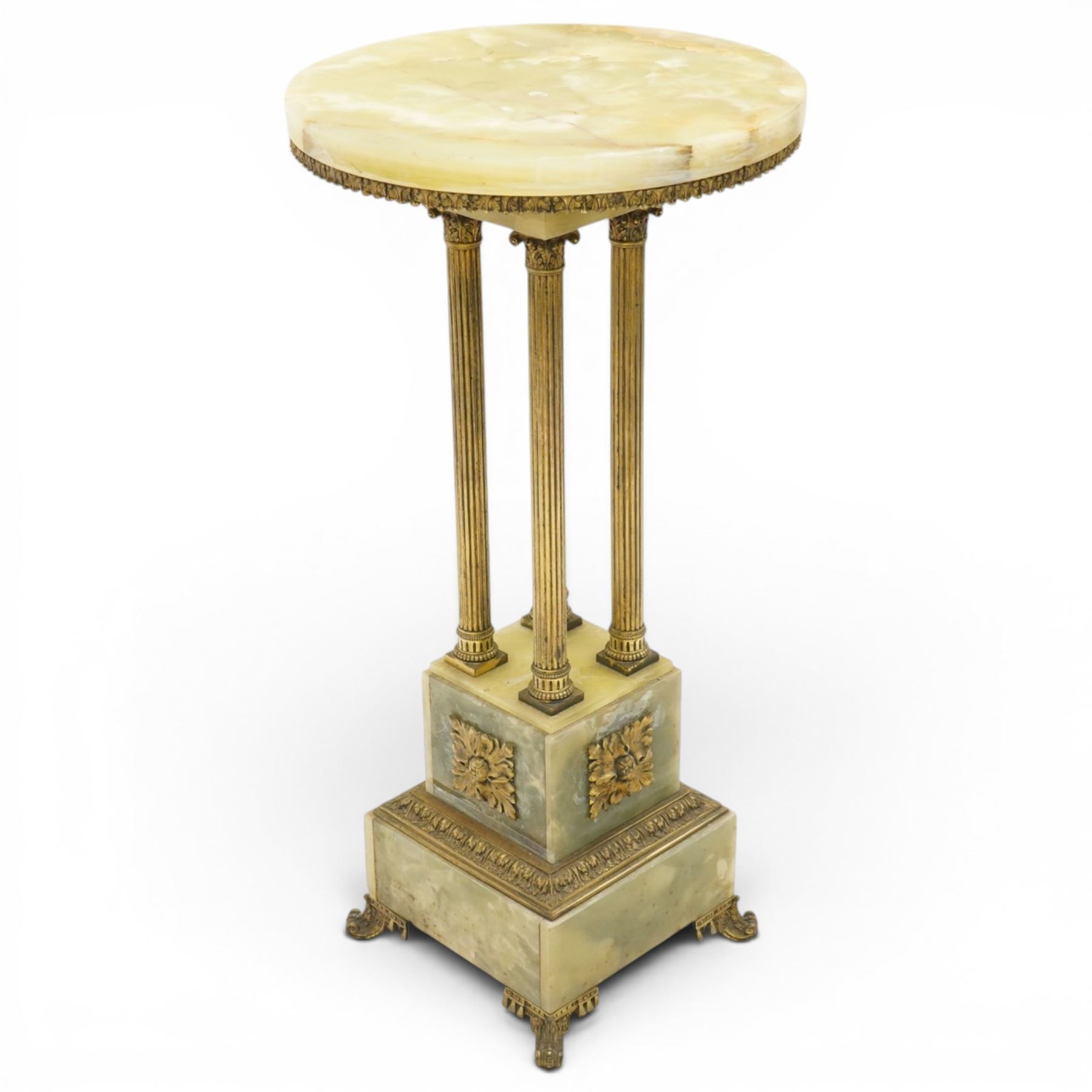 Neoclassical onyx and brass jardinière or plant stand, circular onyx top over an acanthus gilt frieze, supported by for fluted composite columns, square plinth with applied rosette mounts and stepped base, raised on scroll feet  