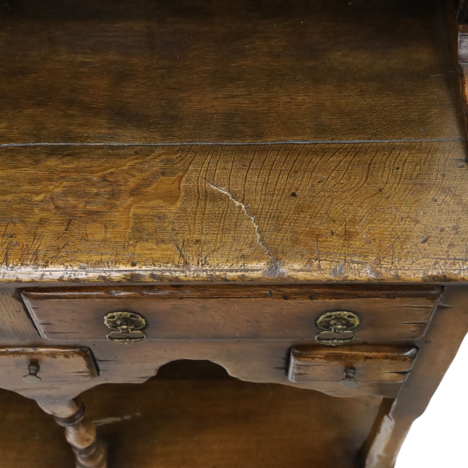 Georgian design oak dresser of small proportions, moulded cornice over open plate rack with two shelves and shaped apron, the base fitted with two drawers over three small drawers, brass drop handles, shaped apron, on square supports united by pot board