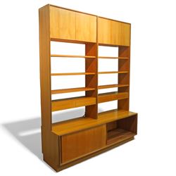 G Plan - 'Form 5' teak modular bookcase unit, comprising two upright sections with upper cupboard compartments enclosed by hinged doors, open adjustable shelving below, fitted with a pair of central drawers to each section, raised over a long base cabinet with sliding cupboard doors