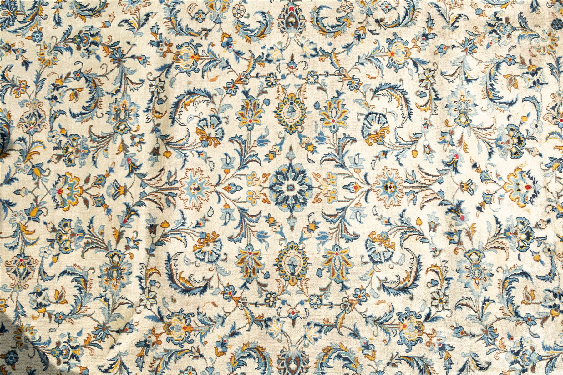 Central Persian Kashan hand-knotted carpet, ivory field profusely decorated with an all-over scrolling vine, palmette, and lotus design in shades of soft blue, pale gold, and green within floral borders