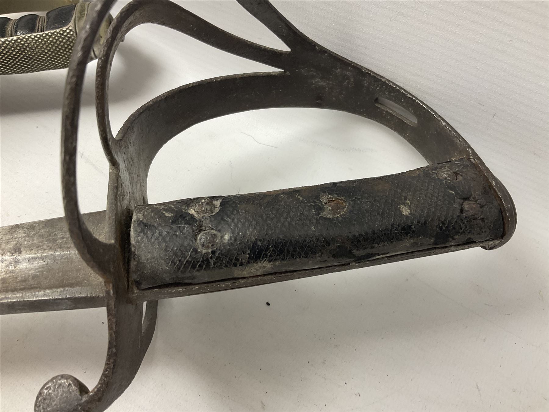 George V British Army 1897 pattern officers sword with plain 82cm fullered steel blade, pierced  basket hilt with George V cypher and wire bound leather grip with chequered backstrap; in leather covered field service scabbard L101cm overall; and another officer's sword in relic condition lacking scabbard (2)