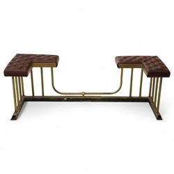 Late Victorian brass and cast iron club fender, burgundy leather buttoned seat pads, secured by bar uprights at the front and back, and a cross stretcher held in place by further bar uprights on a chamfered platform base, circa 1890, internal base dimensions 127cm 