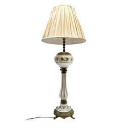 Table lamp in the form of a Victorian oil lamp, the cast metal base with four lion mask and paw feet, leading to a milk glass stem and 'reservoir' with foliate decoration, not including fixtures H68cm, with pleated shade