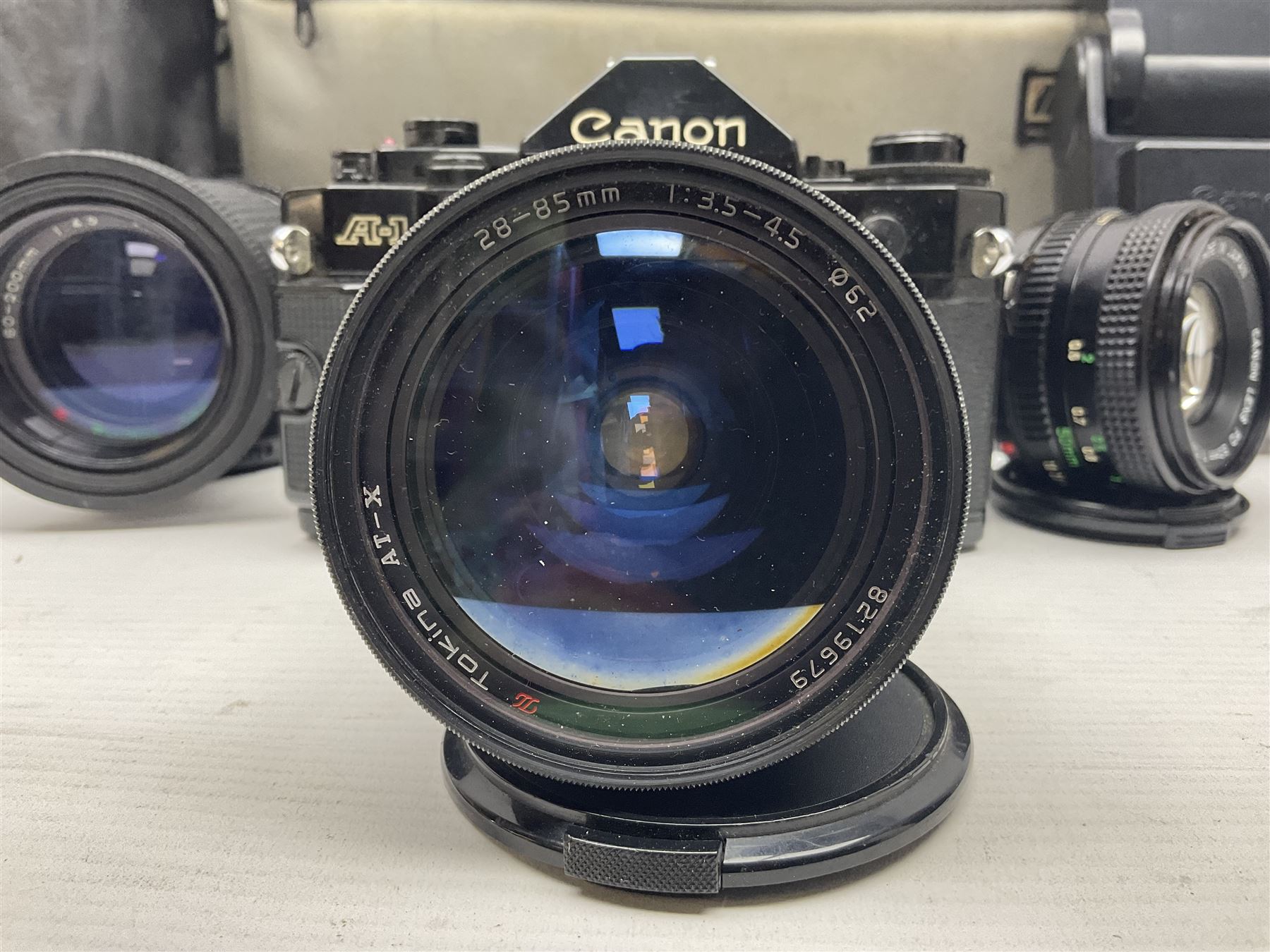 Canon A1 35mm camera body serial no 741264, with 'Tokina AT-X 28-85mm 1:3.5-4.5' lens serial no 821679, 'Canon FD 50mm 1:1.8mm' lens and other camera equipment 