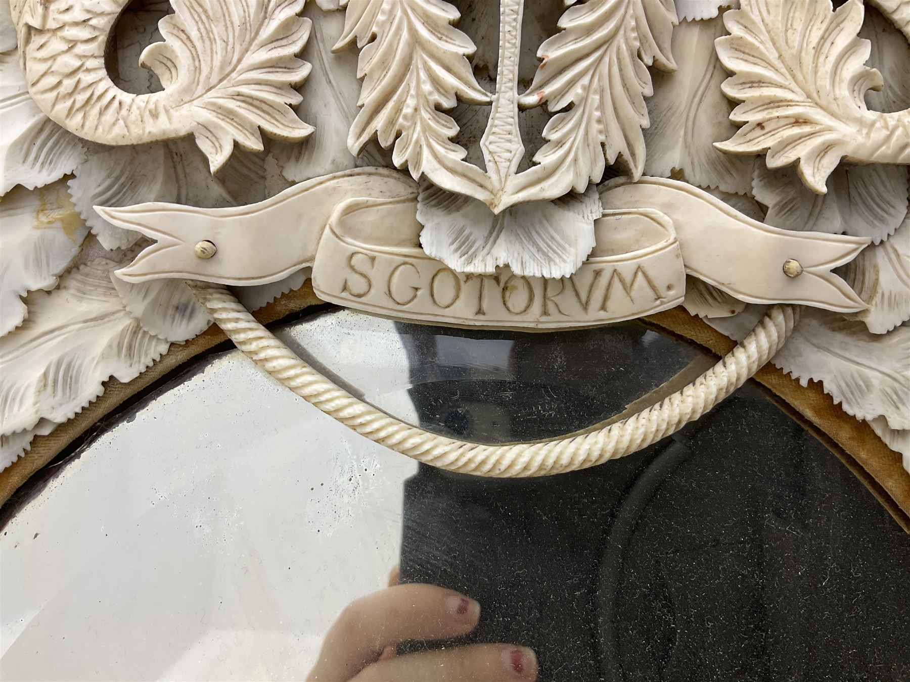 Pair 19th century French Dieppe bone and ivory wall mirrors, the oval bevelled mirror plates within rectangular frames with shaped tops, profusely decorated with ivory leaves, further detailed with carved bone armorial type crest inscribed 'SGOTORVM', putti, fish and mask heads, H81cm W48cm