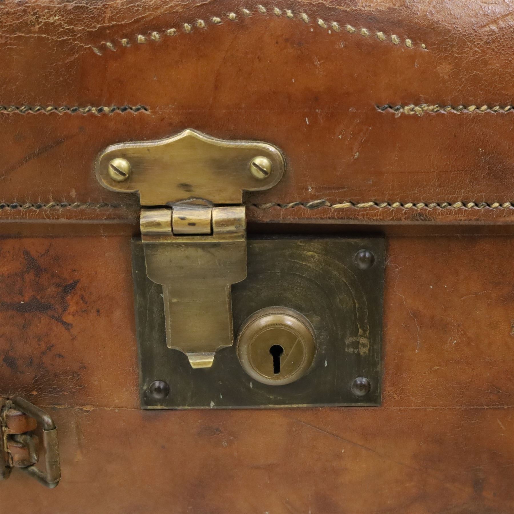 19th century leather trunk, featuring brass lock, with leather anchoring straps around the body, with leather handles