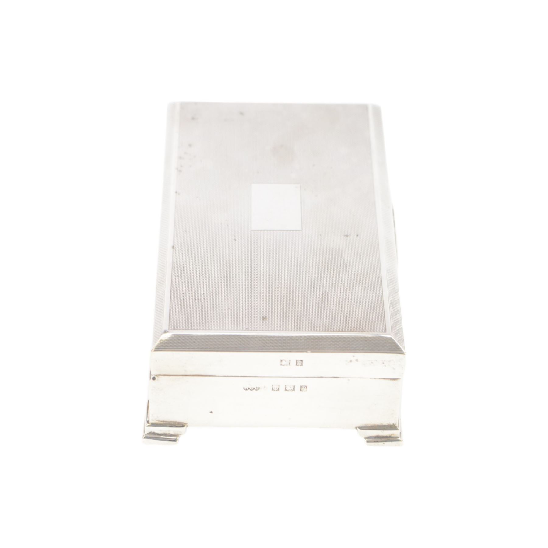 Mid 20th century silver mounted cigarette box, of rectangular form with engine turned decoration to the hinged cover, with vacant rectangular cartouche, opening to reveal a compartmentalised softwood interior, upon four bracket feet, hallmarked Henry Clifford Davis, Birmingham 1964, H4cm, W15cm