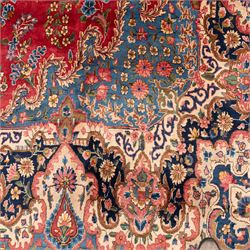 Fine Persian crimson ground Kashan carpet, the busy field with a central floral pole medallion surrounded by bouquets of flowerheads and trailing foliage, the shaped cyan spandrels similarly woven, enclosed by a wide foliate guard band of stylised palmettes and floral designs