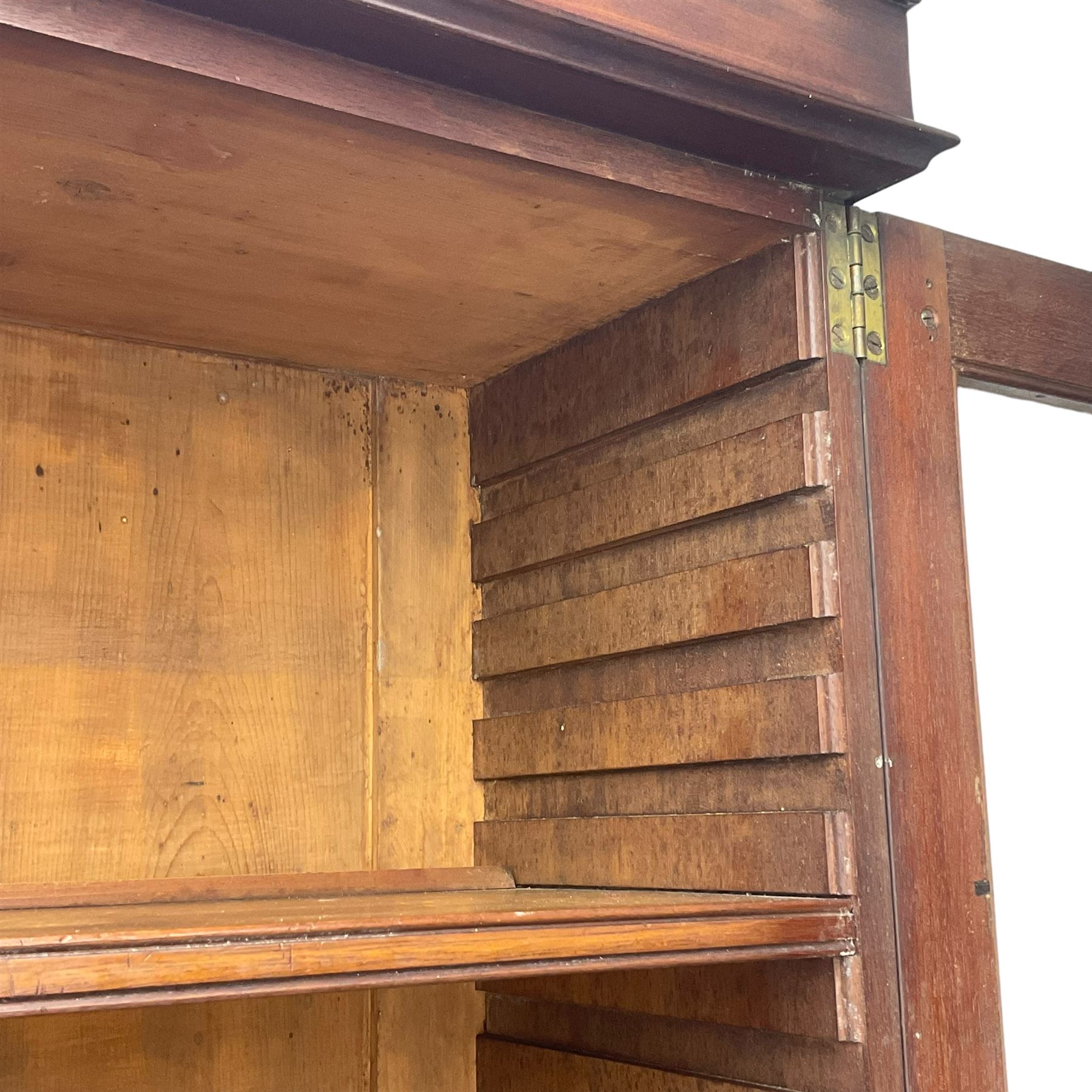 Early 19th century figured mahogany bureau bookcase, projecting splay moulded cornice over three adjustable shelves enclosed by two glazed doors, fall front revealing pigeonholes, cupboard and drawers, pull-out strays with scroll carved terminals, double cupboard with two panelled doors, on turned feet 