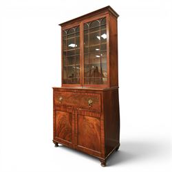 Early 19th century mahogany secretaire-bookcase, projecting cornice above astragal glazed cabinet with adjustable shelved interior, fall front secretaire drawer, fitted interior with pigeonholes and drawers, flame mahogany fronted cabinet with three drawers, on turned supports 