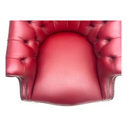 Kingsgate - contemporary 'Devon' bucket armchair, upholstered in red leather with buttoned backrest, rolled arms and brass stud detailing, raised on four dark wood supports with vertical carving