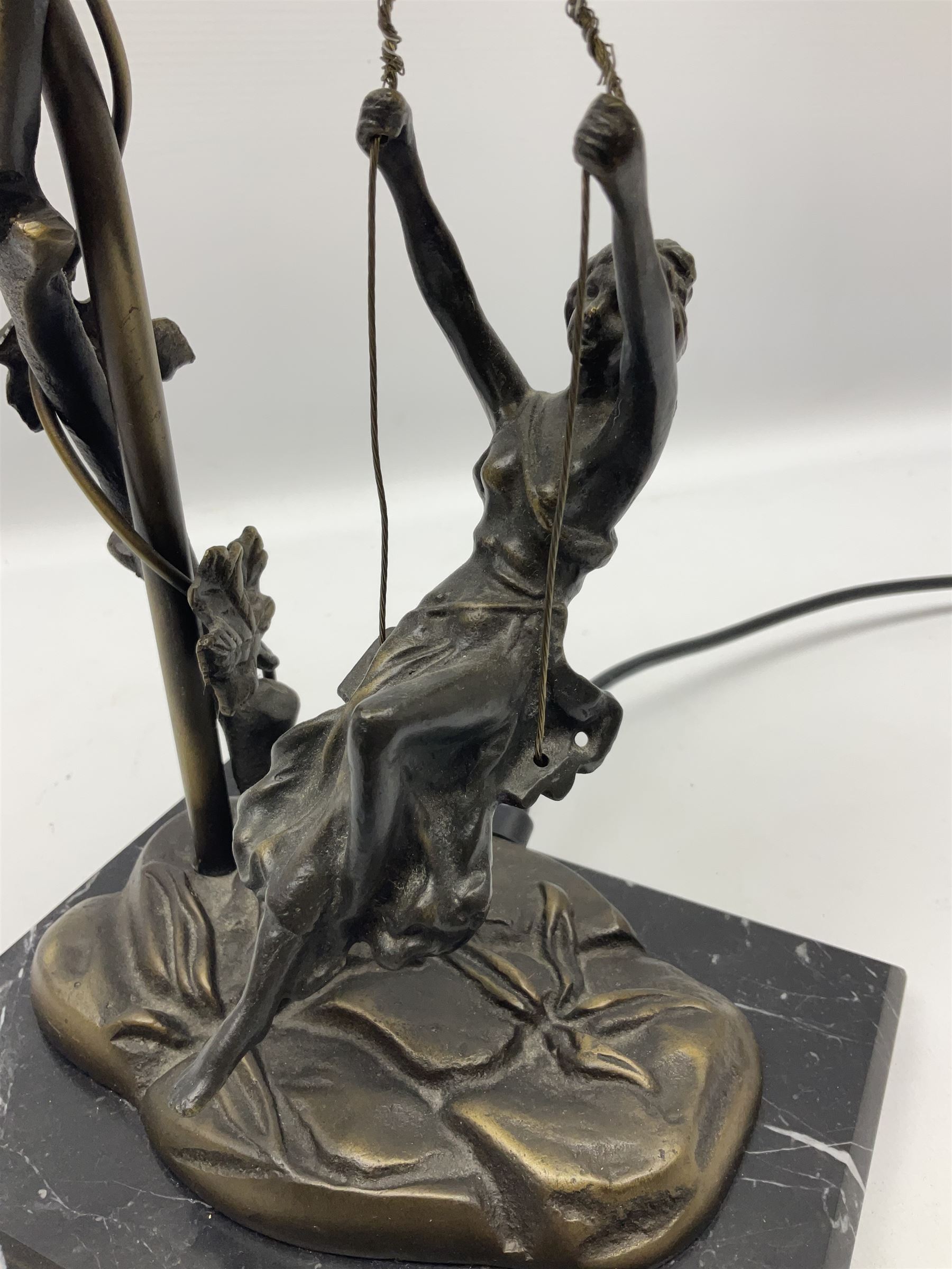 Art Nouveau style lamp in the form of a woman on a swing, with a green mottled shade, upon a marble base H52cm
