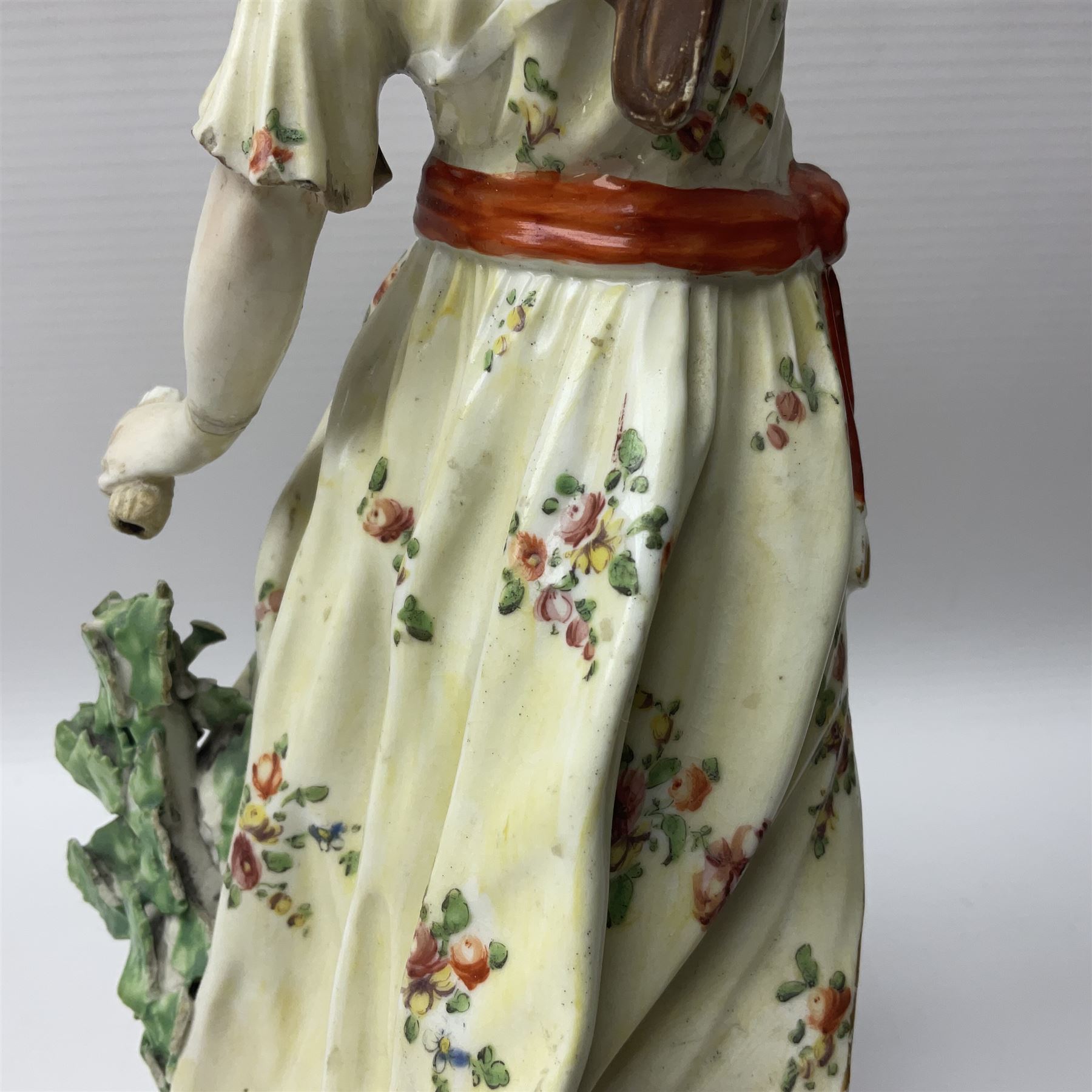 18th century Derby figure of Diana the huntress, circa 1760, modelled reaching for an arrow from quiver across her back, with recumbent hound at her feet, upon a scrolled base with bocage detail, H27.5cm