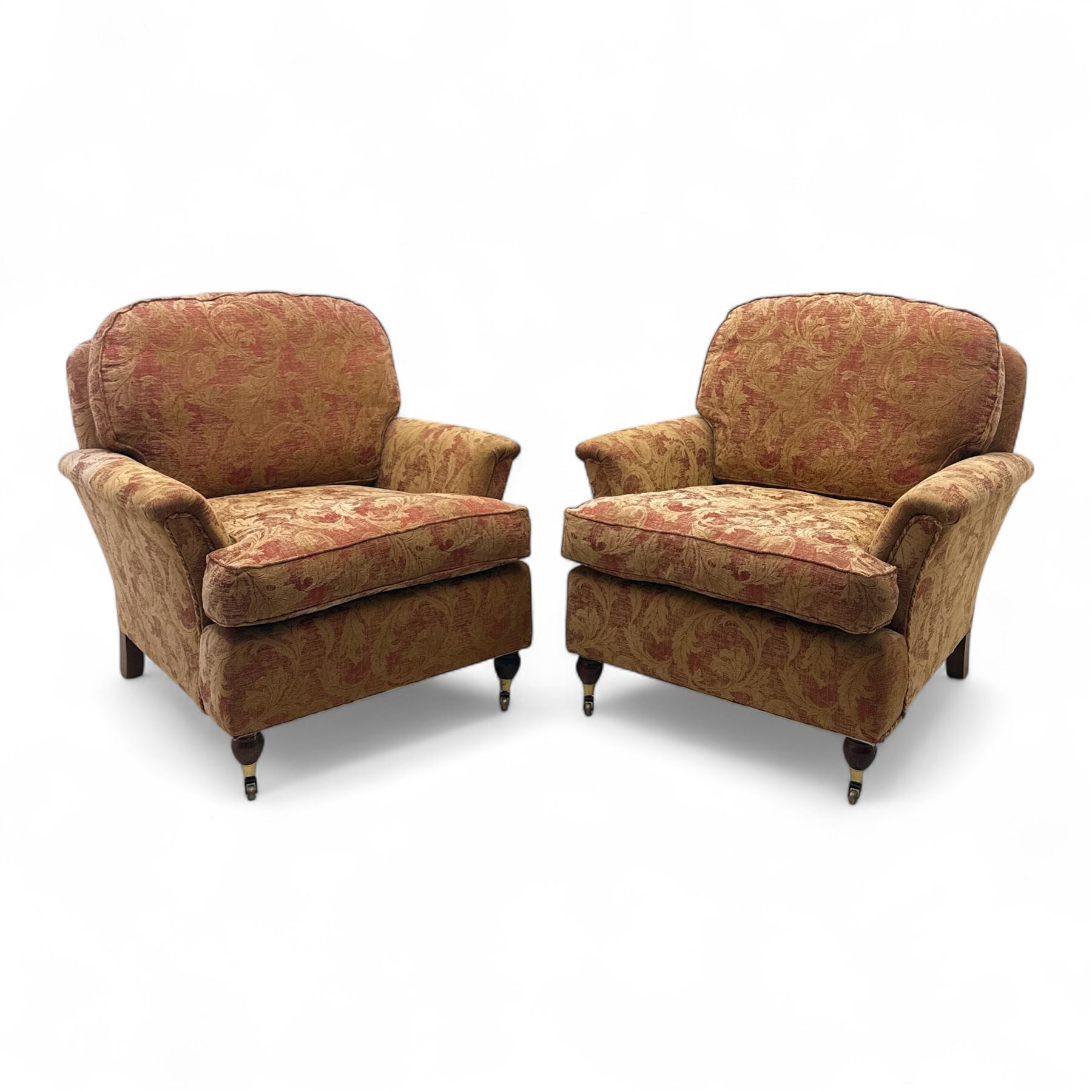 Duresta - Contemporary pair of upholstered armchairs, in red and gold damask style fabric, each with sprung seat and removable cushion back, rolled arms, on turned front supports with brass castors, square back legs 