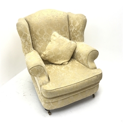 Licoln House wing back armchair, upholstered in a pale gold chenille fabric with floral pattern, shaped back, scrolled arms on turned supports, W91cm