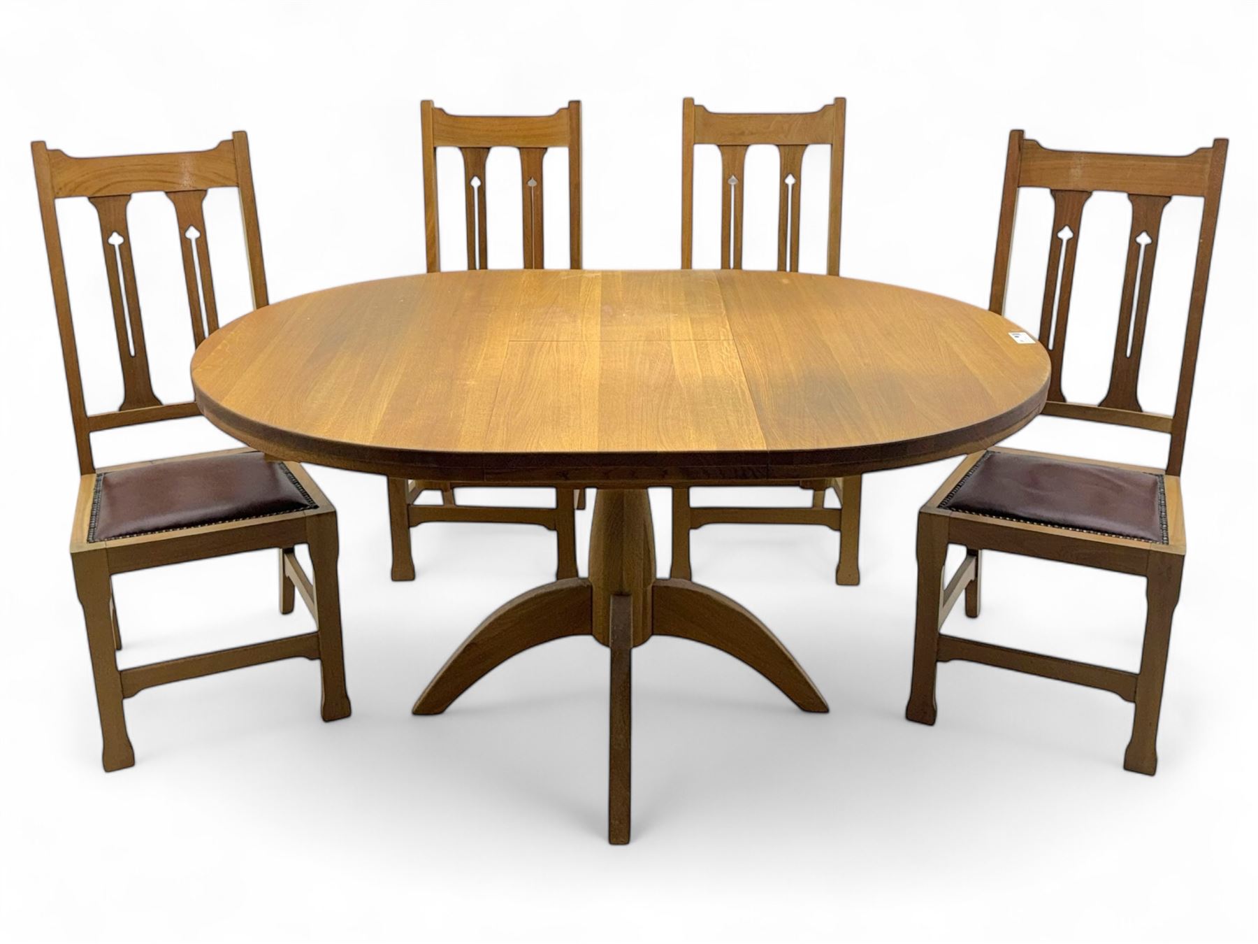 Contemporary light oak round extending dining table with four chairs, table has fold out leaf attached underneath on four out-swept legs, Oak chairs with straight top rail over twin slat back with pierced motifs, brown leather seat with brass studs, square legs joined by plain stretcher 