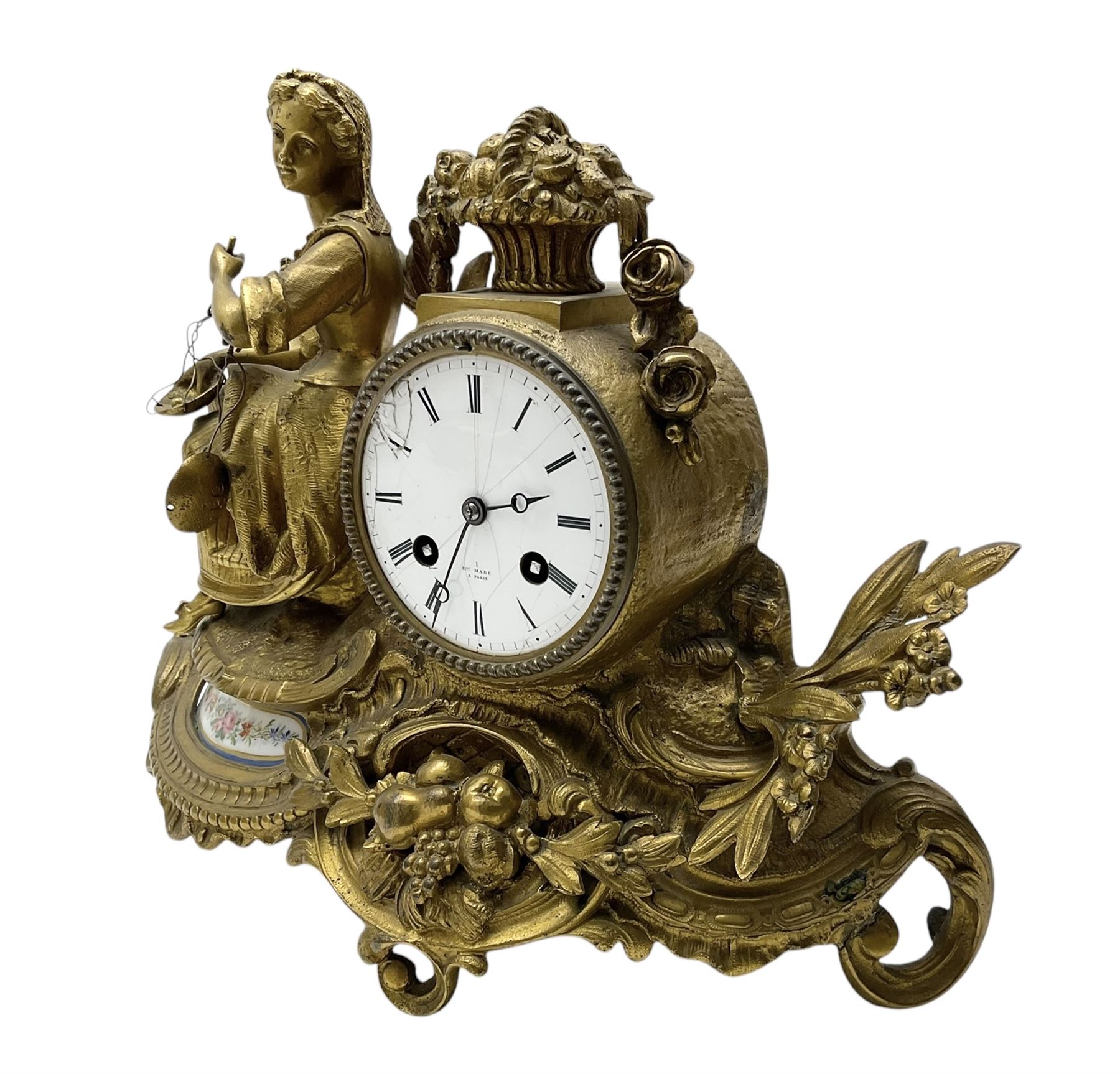 French-Gilt-metal mantle clock c1870, with a seated figure of a lady holding a pair of scales, on a scroll base with a porcelain panel on a blue ground depicting a floral spray of flowers, with brass castings of fruit and foliate decoration, enamel dial signed Henry Marc, Paris, with Roman numerals and steel moon hands, twin train countwheel striking movement sounding the hours and half-hours on a bell. With pendulum and key.