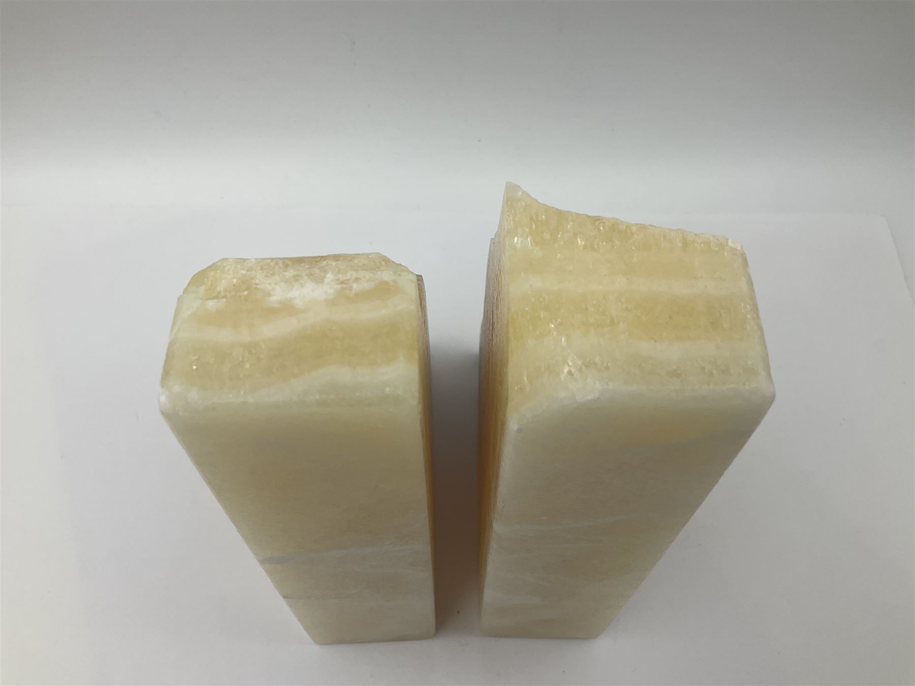 Pair of honey onyx bookends of rectangular form with polished to three sides with a raw outer edge, H18cm 