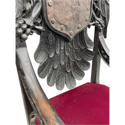 Grand mid-to-late 19th century heavily carved beech framed throne chair, the crown pediment carved with flower heads and cross finial, scroll and acanthus carved upright supports with twin perching griffin back enclosing etched leather work heraldic shield with castle and lion motifs over splayed feathers, flower head carved down sweeping arms with grotesque carved terminals, the seat rails carved with further flower heads on moulded supports with oversized ball and claw carved feet

Provenance: A very similar chair was used in the filming of Stanley Kubrick's 'Eyes Wide Shut' (1999)
