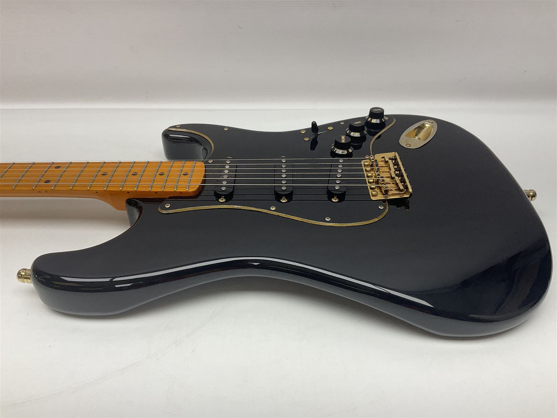 Copy of a Fender Stratocaster electric guitar in black with Wilkinson bridge, lock-in tuners, synchronised tremolo and various patent numbers; L99cm; in hard carrying case with strap and digital tuner