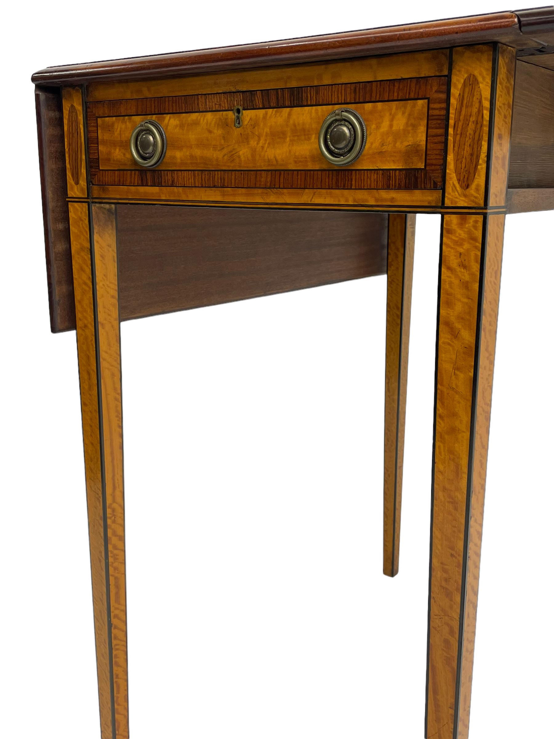 Mid-to-late 20th century Sheraton style satinwood Pembroke table, the drop leaf top with segmented veneers and central oval panel with ebony stringing, crossbanded in rosewood and with edge moulding, single short drawer to one end and faux drawer to other, square tapering supports