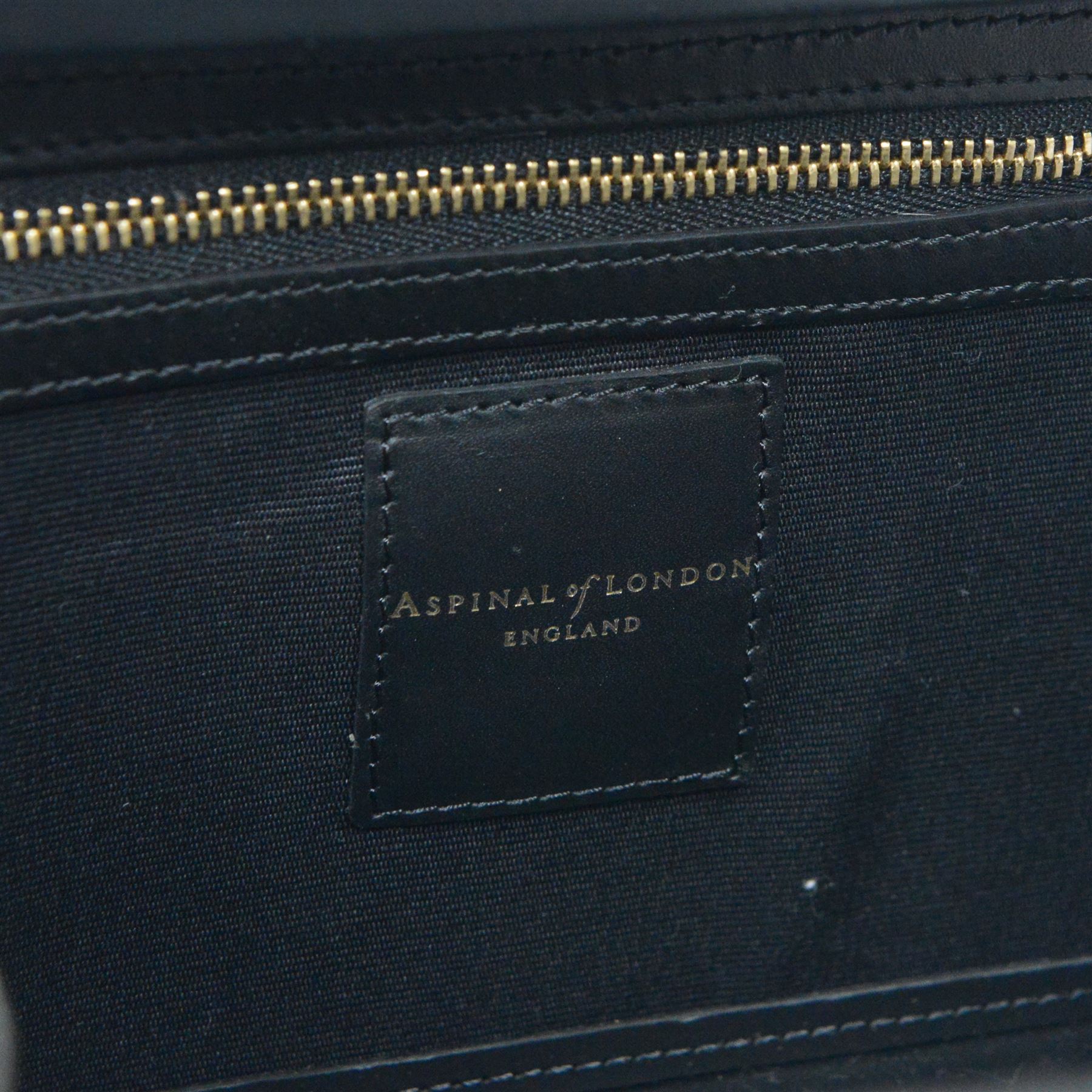 Aspinal of London black leather structured top-handle handbag with gold-tone metal mounts and corner protectors, the hinged lid opening to a fabric-lined interior fitted with a zip pocket and slip compartment, leather brand label stamped Aspinal of London England, fitted with a detachable adjustable leather shoulder strap, accompanied by an Aspinal of London dust bag and presentation box, W19cm D8cm H16cm