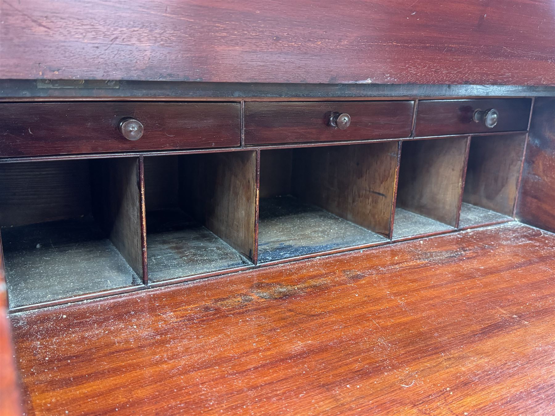 Large Victorian mahogany Registry/Dickens’ desk, spindle gallery top, one side with five small drawers and the other with blind cupboard drawer, revealing pigeon holes with scroll carved locking side bars on either side, above a hinged and leathered writing slope with three drawers and pigeon holes underneath, above a central locking drawer with key, the pedestals each with four drawers and  turned knob handles, separates into four parts for transport
