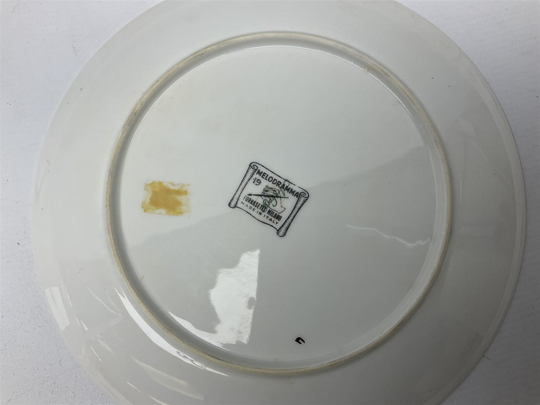 Three Fornasetti plates from the Melodramma series, each depicting a operatic portraits within a border of operatic emblems on gilt ground, with printed mark beneath, D25cm 