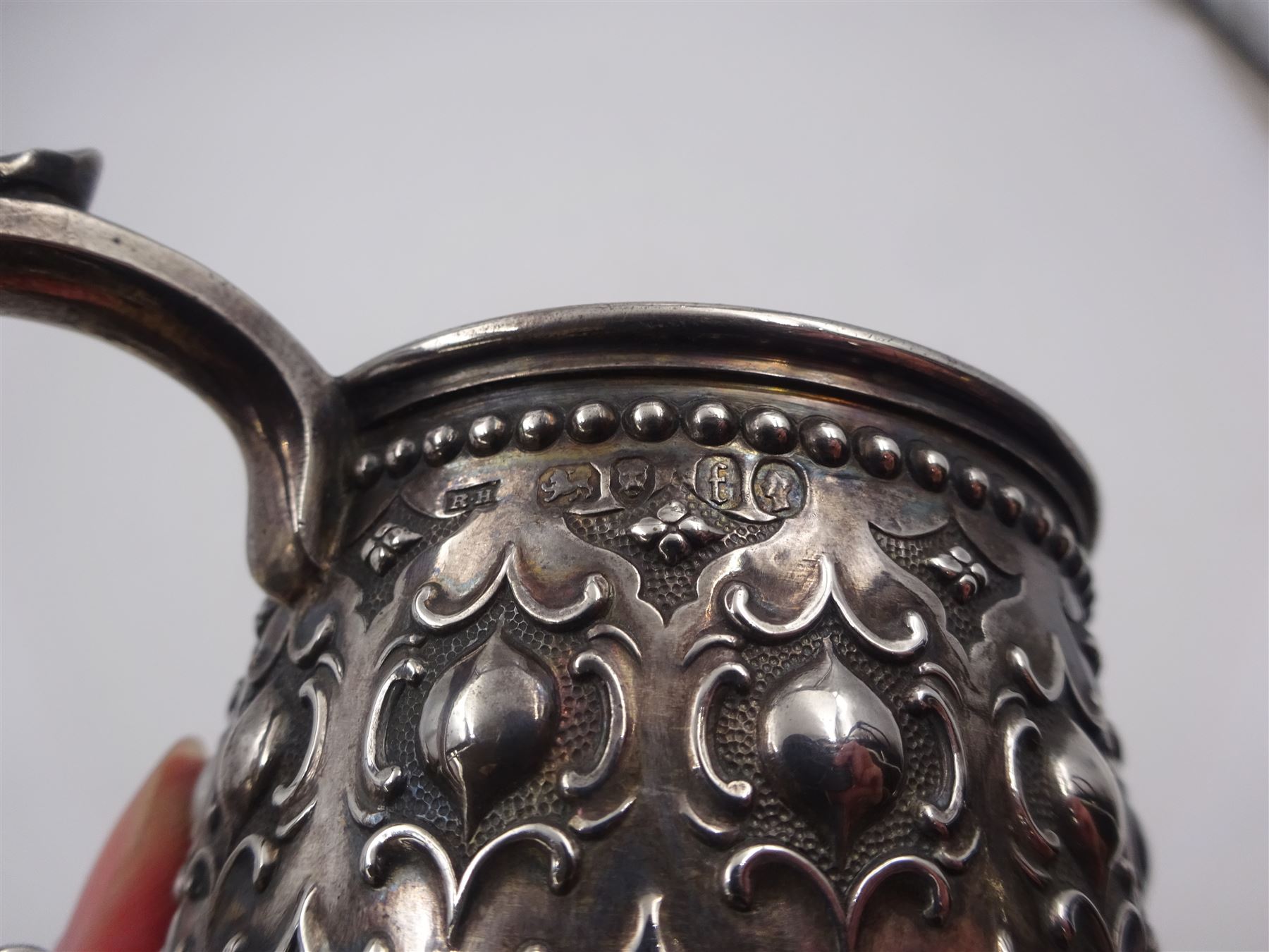 Victorian silver christening mug, with repousse and chased scroll and bead decoration, lozenge shaped cartouche engraved with monogrammed initials and acanthus capped C scroll handle, hallmarked Robert Hennell III, London 1861, H9.3cm