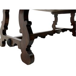 Large Spanish hardwood dining table, on shaped open ends supports joined by stretcher 
