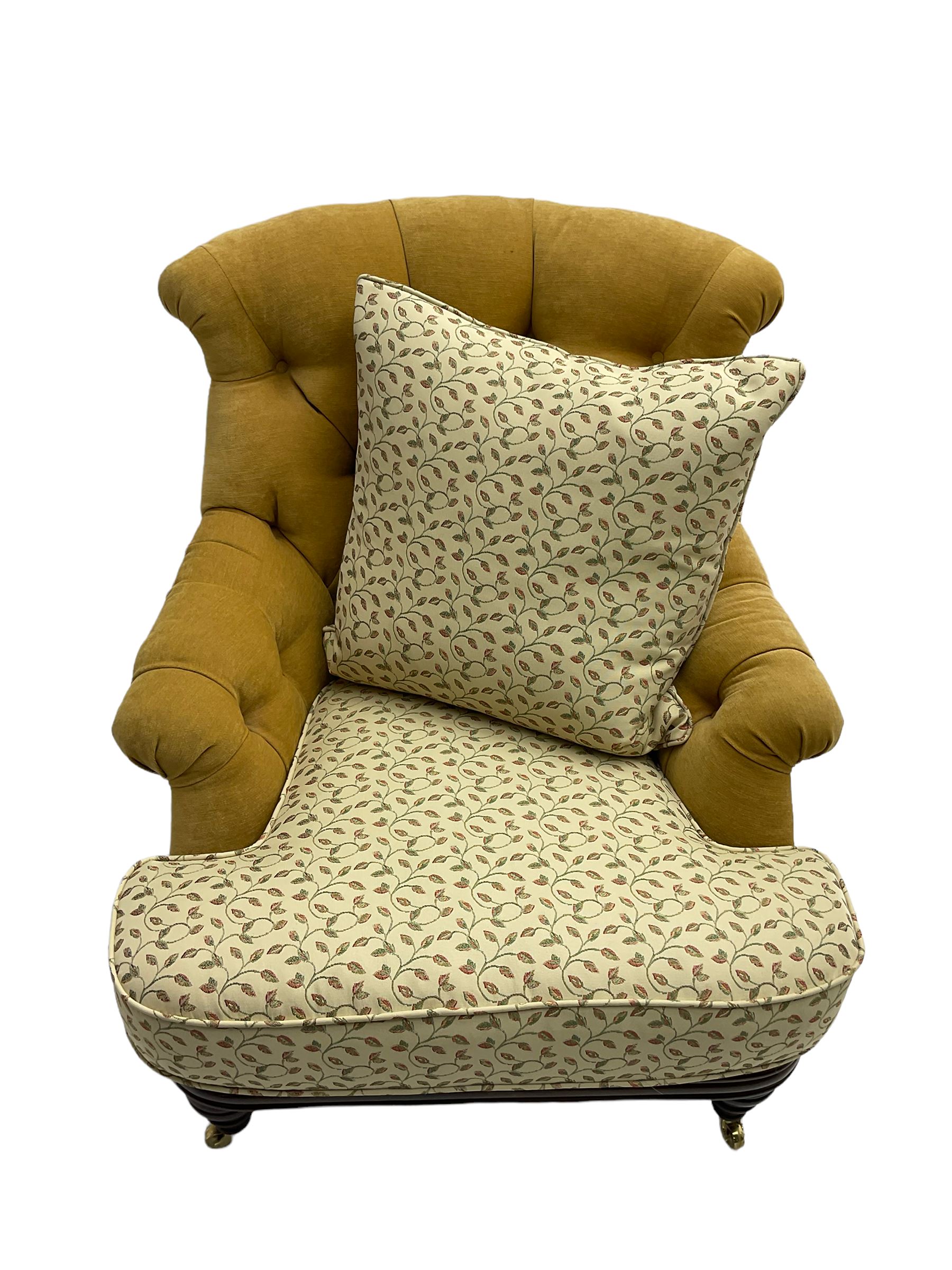 Victorian style armchair, upholstered in buttoned fabric with contrasting foliate pattern seat and scatter cushion, on turned front feet with castors