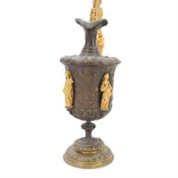 Pair of bronzed and gilt ewers in the Neo-Classical taste, each of typical form with figural detailed and mounted scroll handle surmounted by a winged figure, the bodies cast with scrolling strapwork, flower heads and acanthus leaves, and further detailed with applied gilt classical figures to oval recesses, upon a knopped stem and spreading circular foot with conforming cast detail, H28cm