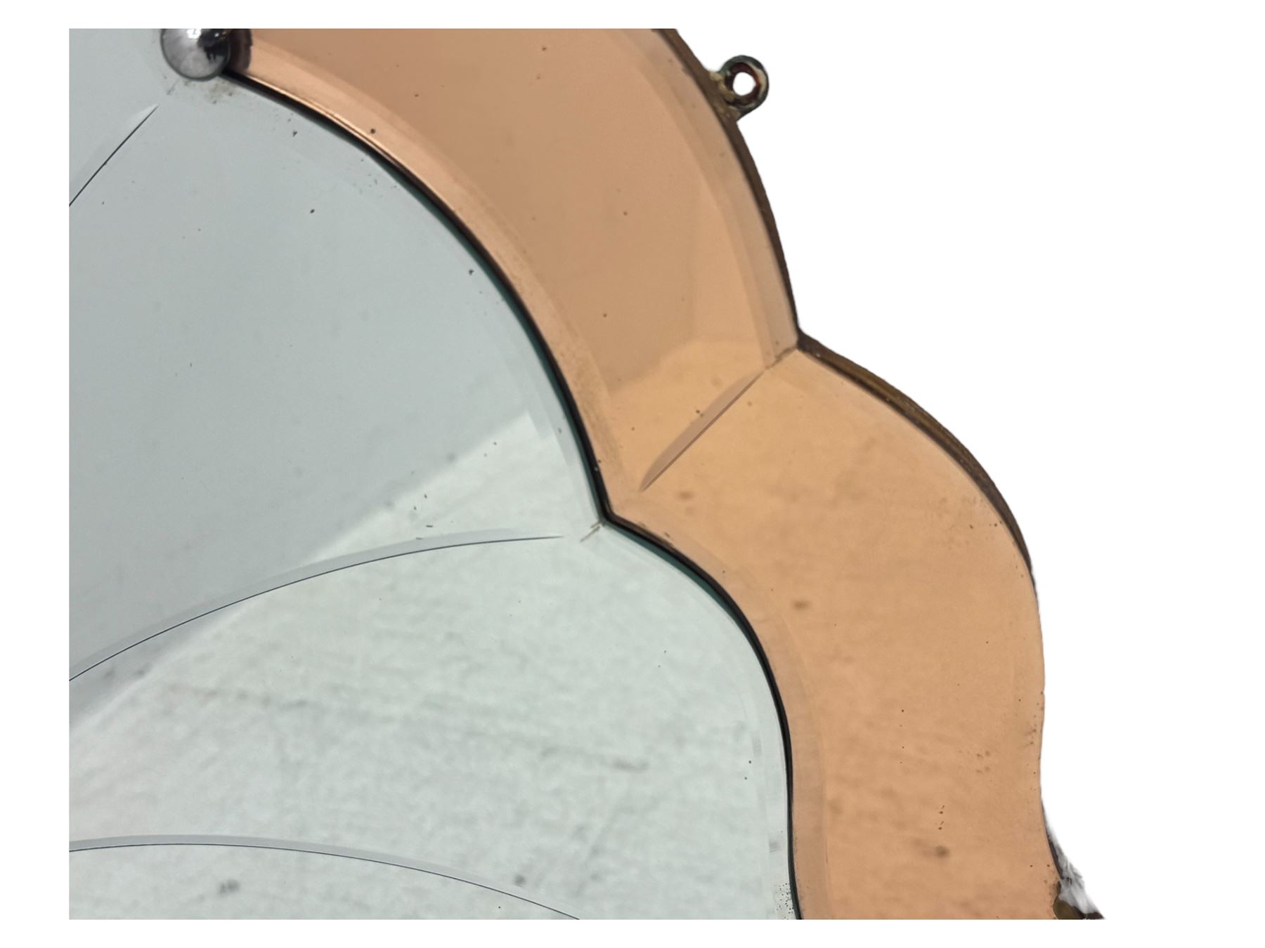 Frameless art deco mirror, scalloped copper tinted border central fan motif, bevelled edges with decorative screw caps