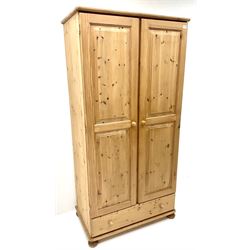 Solid pine double wardrobe, two doors enclosing hanging rail above single drawer, turned supports 