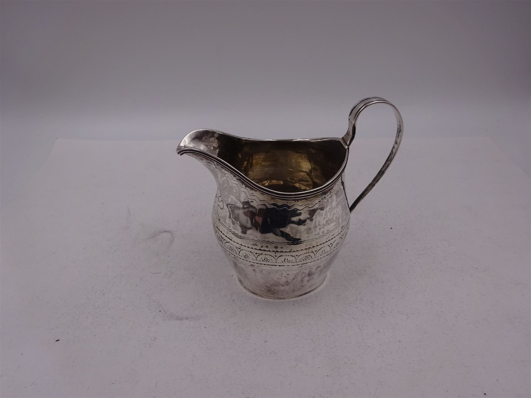 George III silver cream jug, of helmet form, with C scroll handle and a band of engraved strapwork decoration and monogrammed initials to body, hallmarked London 1802, maker's mark SA probably Stephen Adams I, including handle H10.4cm