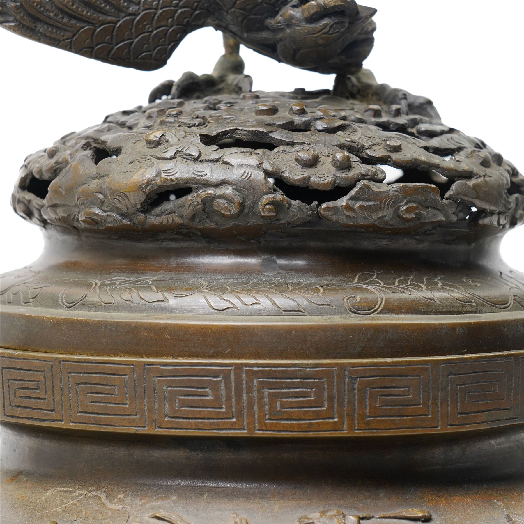 Japanese Meiji period bronze Koro, c.1870-1880, of squat baluster form, each foot with elaborate floral and mythical creature decoration, the body depicting two lions in chase, the rim with Greek key border, the pierced cover with eagle finial, Yoshida foundry mark to base, H50cm