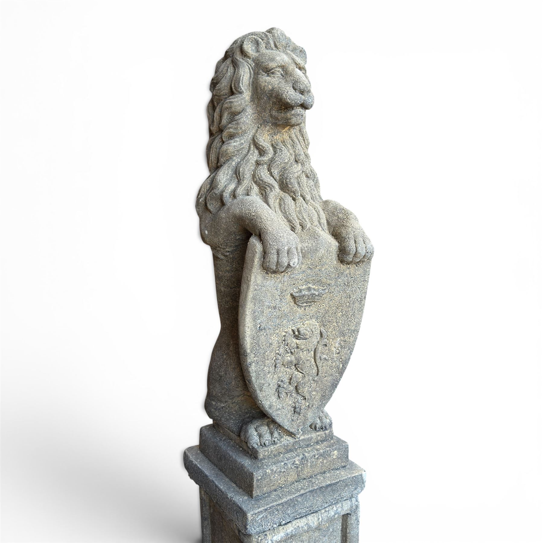 Pair of cast stone Heraldic lions, modelling in upright standing poses with flowing mane, each clasping an Armorial shield moulded with a crowned lion in their forepaws, raised on rectangular pedestals