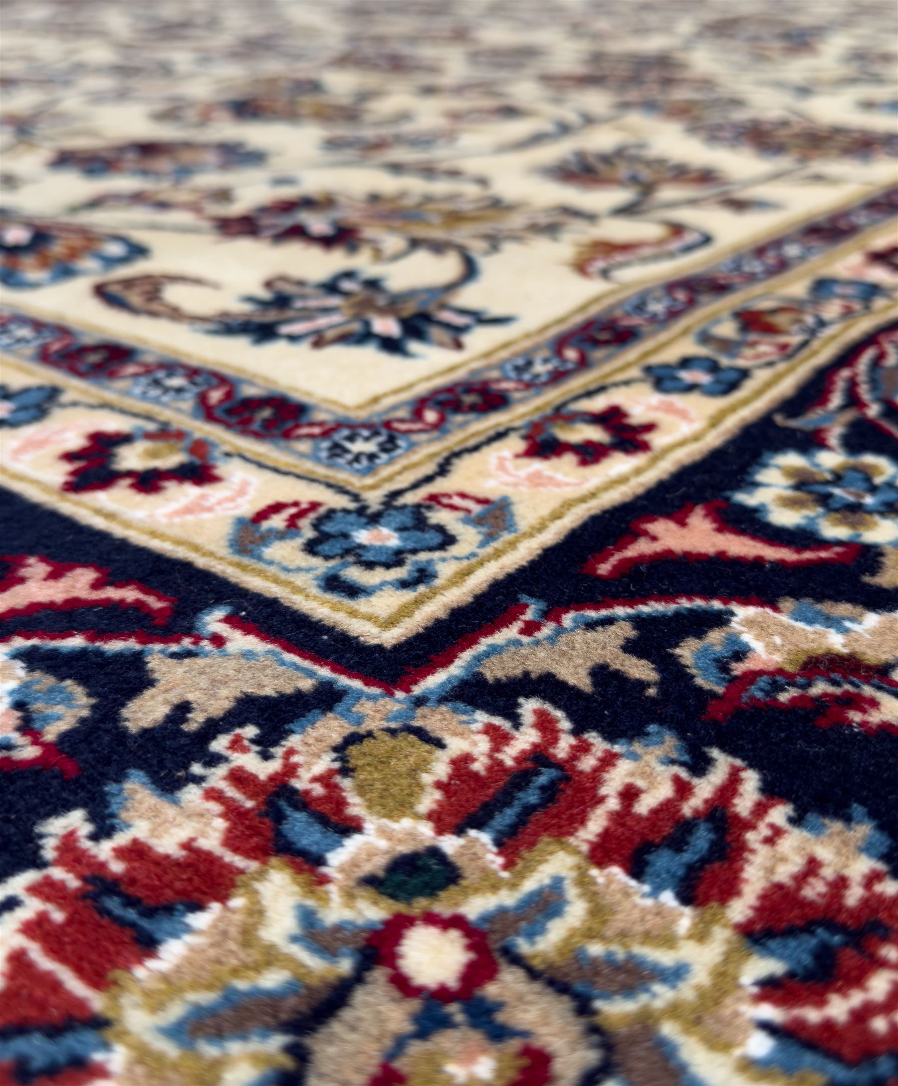 Northeastern Persian Meshed hand-knotted rug, ivory ground with an overall design of scrolling vines, palmettes, and rosettes in an indigo palette, soft blues, and madder, framed by a deep indigo border of lotus palmettes and flowerheads between multiple guard borders, 300cm x 202cm