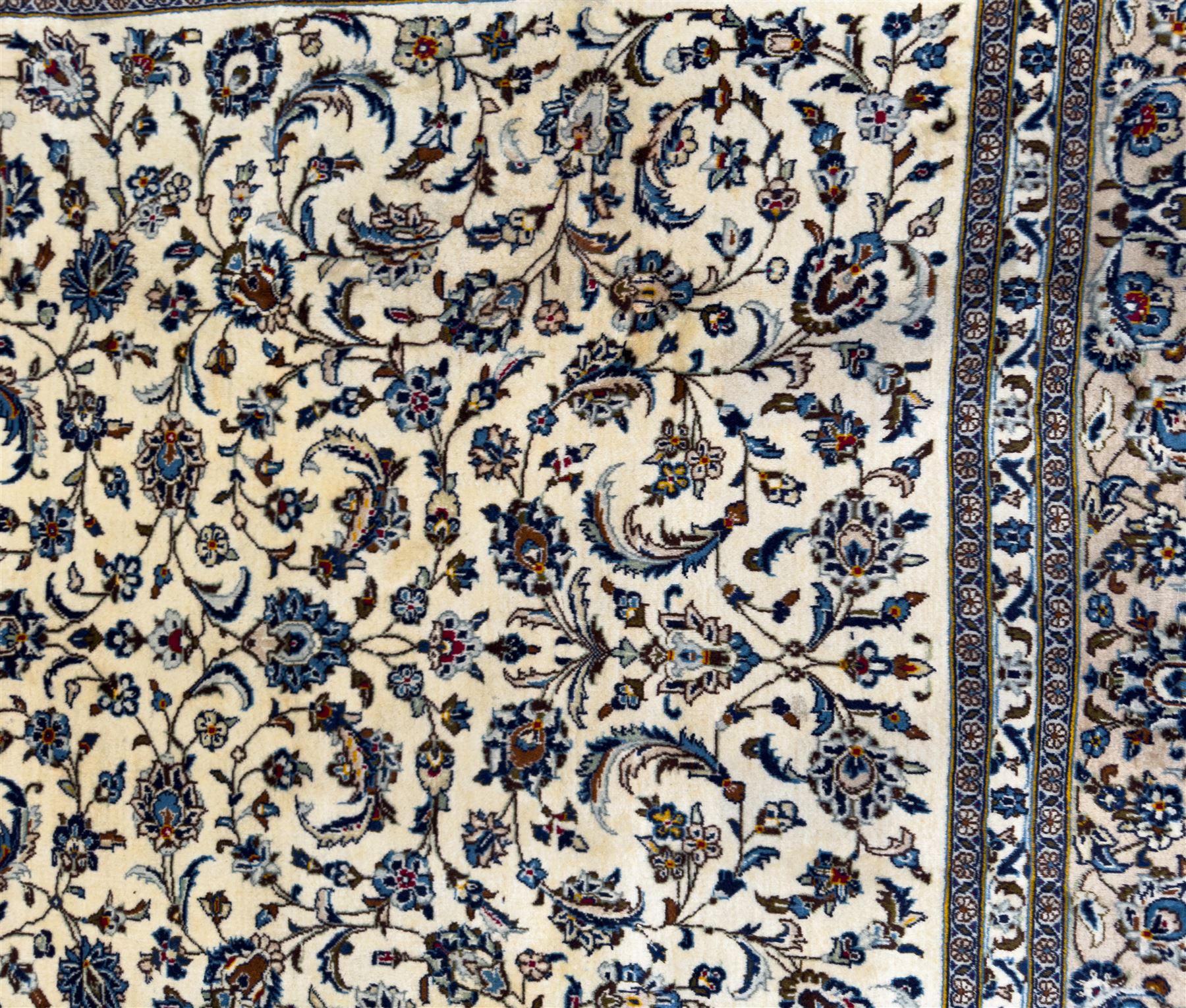Central Persian Kashan hand-knotted carpet, ivory field with an all-over design of scrolling vines, lotus palmettes, and rosettes in shades of blue and brown within a blue ground border of palmettes and arabesques between multiple guard stripes, 
348 cm x 246cm