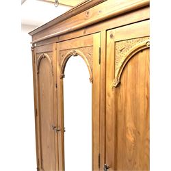 Gothic triple pine wardrobe, projecting cornice, central cupboard door with bevelled edge mirror, flanked by two cupboard doors enclosing shelving and hanging rail, above three short and two long drawers, shaped plinth base