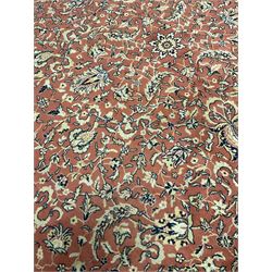 Persian design red ground carpet, the field decorated with interlacing foliage and stylised flower heads, repeating scrolling boarder with plant motifs