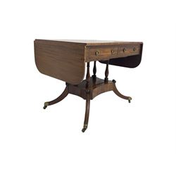 Regency period mahogany drop-leaf sofa table, rectangular top fitted with two cockbeaded drawers with ebony stringing, raised on turned columns united by quadrupod base, the sabre supports terminating in brass cups and castors