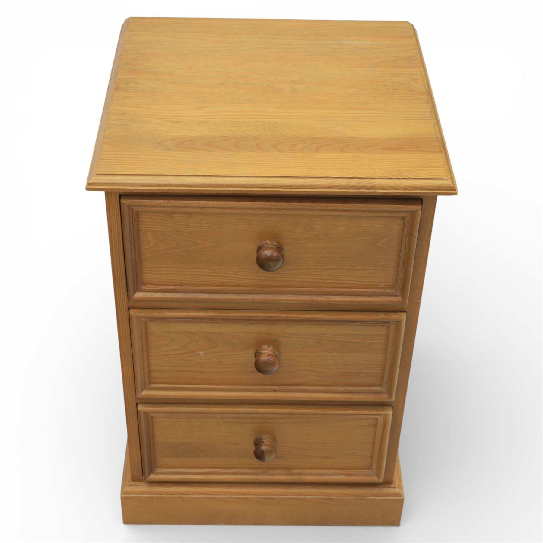 Pair of late 20th century waxed pine bedside chests, three drawers with moulded edges and turned pulls, raised on a plinth base 