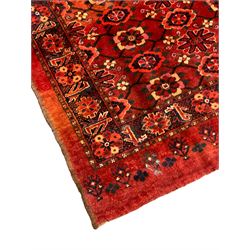 Persian red ground rug, the field decorated with lattice pattern and flowerhead, repeating border decorated with flower heads and leaf motifs
