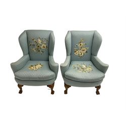 Pair of 20th century Queen Anne design stained beech framed wingback armchairs, upholstered in light blue fabric with raised floral pattern needle work, rolled arms and upholstered seat cushion, on shell carved cabriole feet with ball and claw terminals 