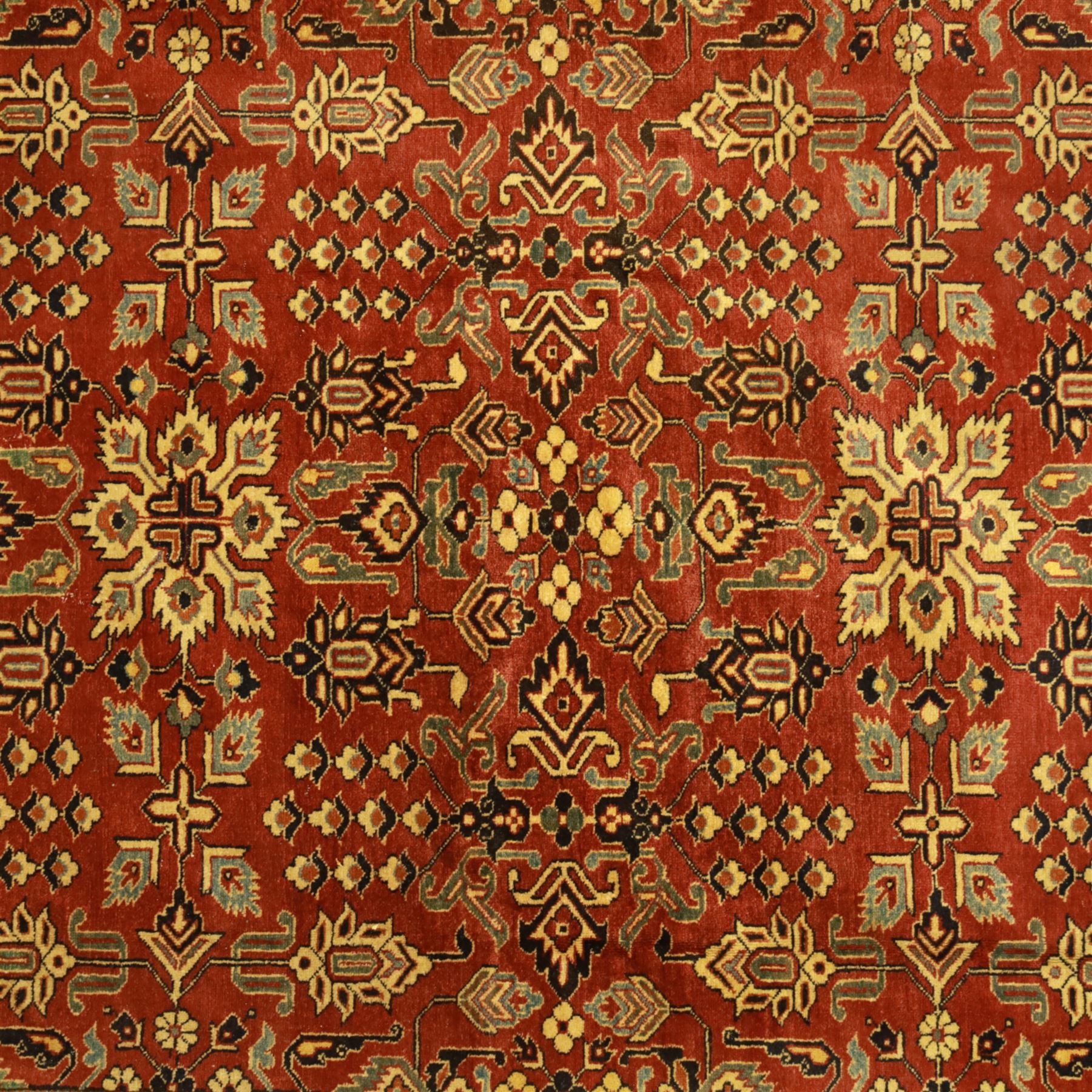 Afghan Gazni Kazak rug, the hand-knotted wool pile featuring a rust red ground with all-over geometric floral motifs in ivory and dark green, enclosed by a wide ivory border with stylised rosettes and angular vine decoration, fringed ends, from the region of Ghazni, Afghanistan